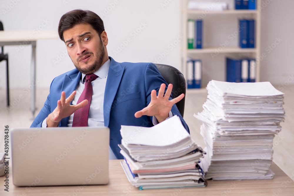 Young male employee and too much work in the office Young male employee and too much work in the office