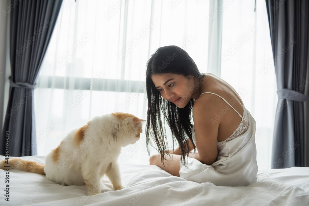 Asaian woman look and play cat on bed in morning Asaian woman look and play cat on bed in morning