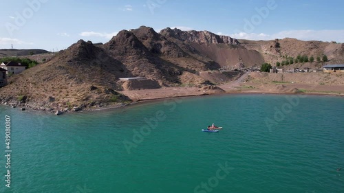 A group of people ride sup surfing in the lake. Aerial view from the drone of the green water and rocky beaches. Inflatable sapboard board. Trees and bushes grow on the bank of Kapchagai. photo