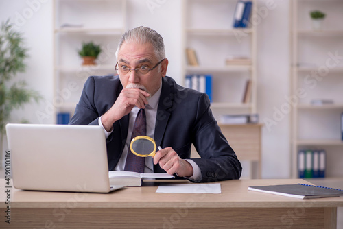 Old male employee sitting at workplace