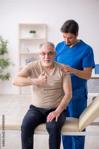Old male patient visting young male doctor chiropractor
