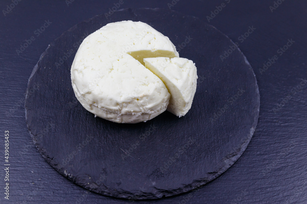 Soft Adyghe cheese on black slate background Soft Adyghe cheese on black slate background