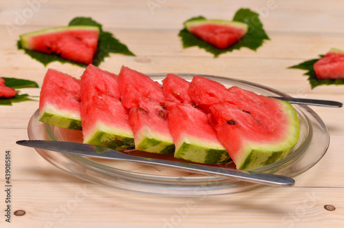 slices of watermelon on a plate and cutlery serving close-up