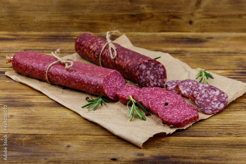 Salami sausages on craft paper on a wooden table Salami sausages on craft paper on a wooden table