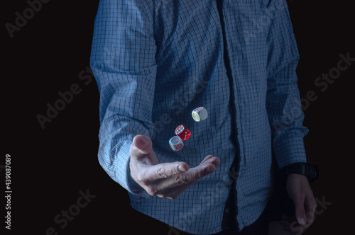The man tosses the dice. Three cubes in the air. A man in a plaid shirt.