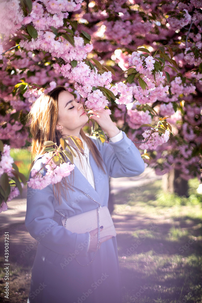 Obraz premium Spring portraits of a gorgeous young woman against a background of cherry blossoms. Japanese garden