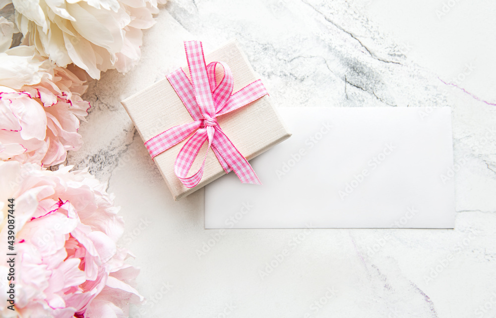 Pink peonies with empty card and gift box on white marble background Pink peonies with empty card and gift box on white marble background