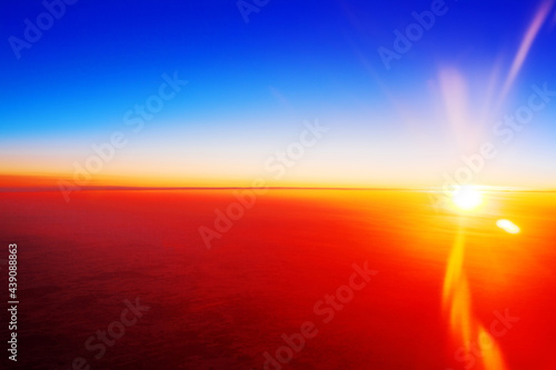 Sunset landscape  colorful sunrise over planet Earth  blue sky  bright yellow sun light rays  red sunbeams  vibrant cosmic sunlight flare  space dawn  cosmos sundown  celestial body view from airplane