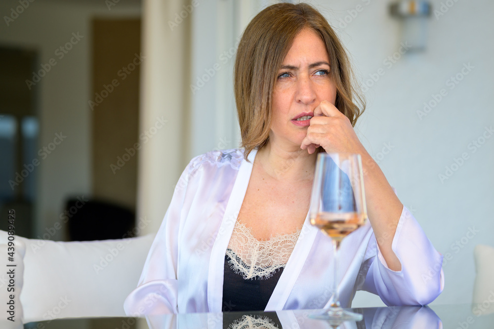 Introspective woman sitting deep in thought at a patio table Introspective woman sitting deep in thought at a patio table