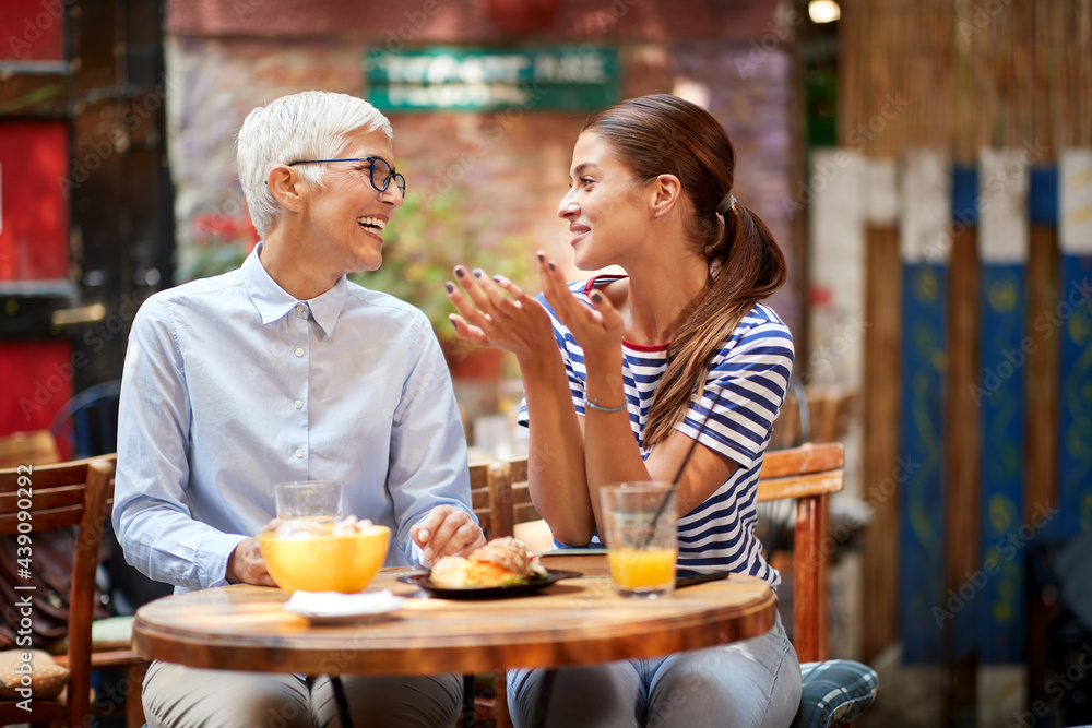 beautiful young adult caucasian woman talking with elderly female, looking each other, smiling. beautiful young adult caucasian woman talking with elderly female, looking each other, smiling.