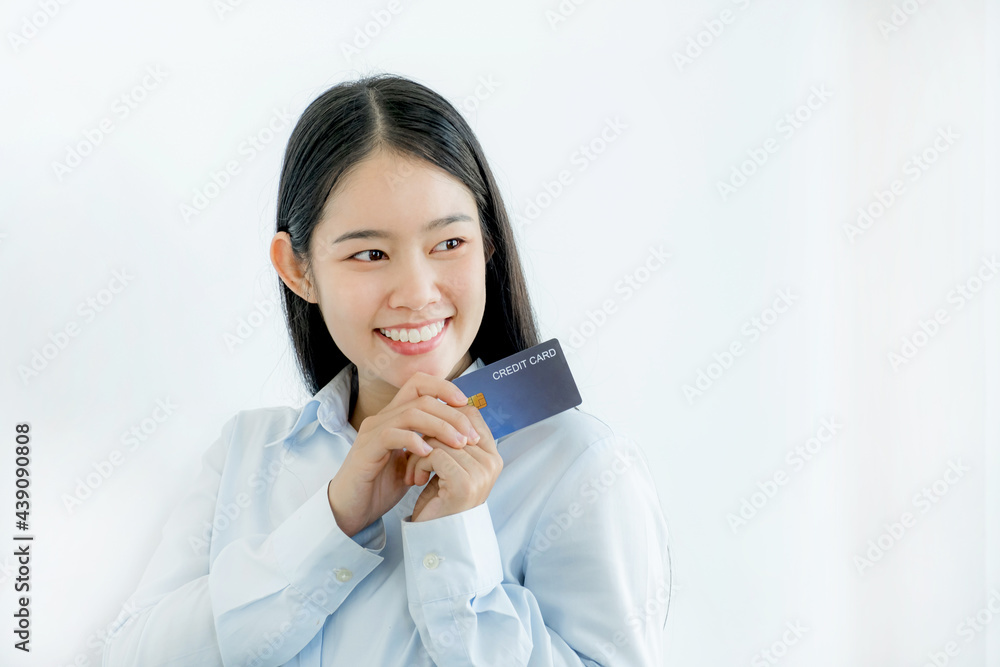 Portrait of a lovely young Asian beautiful woman with long hair holding a blue credit card, her eyes sparklingly at the camera. Ready to pay shopping according to discounted products Portrait of a lovely young Asian beautiful woman with long hair holding a blue credit card, her eyes sparklingly at the camera. Ready to pay shopping according to discounted products