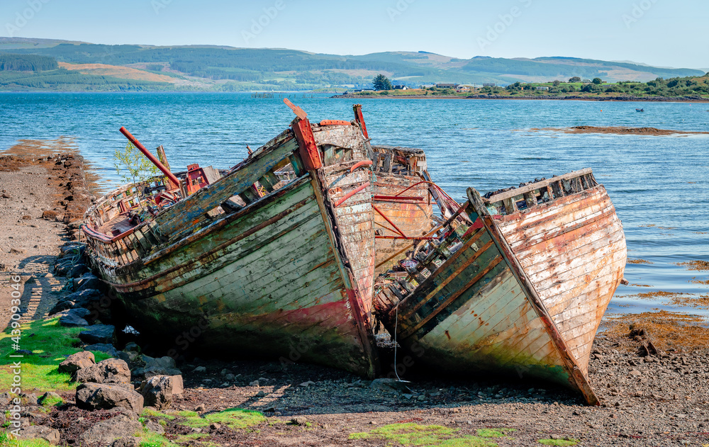 Fishing boat wrecks at Salen, on the Isle of Mull. The Sound of Mull is in the background. 
Scotland, August 2019.