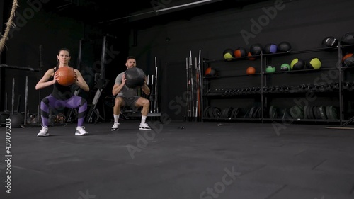 Beautiful young sports couple is working out with medicine ball in gym slow motion.