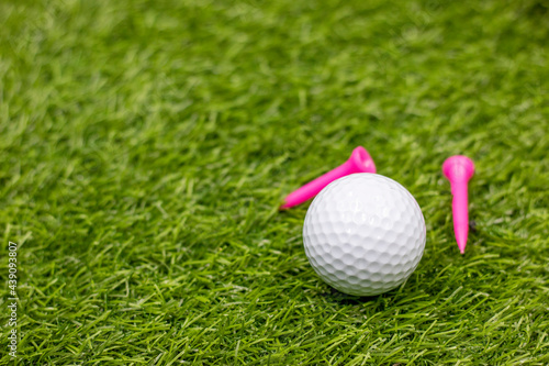 Golf ball with pink tee on green grass for Breast Cancer Awareness