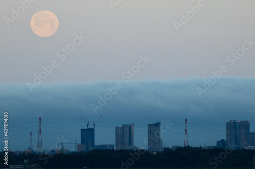 低い雲に包まれた高層ビルと満月