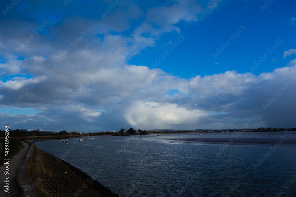 exit of the Exeter Ship Canal at Topsham with a few clouds reflected in the still water and a clear blue sky