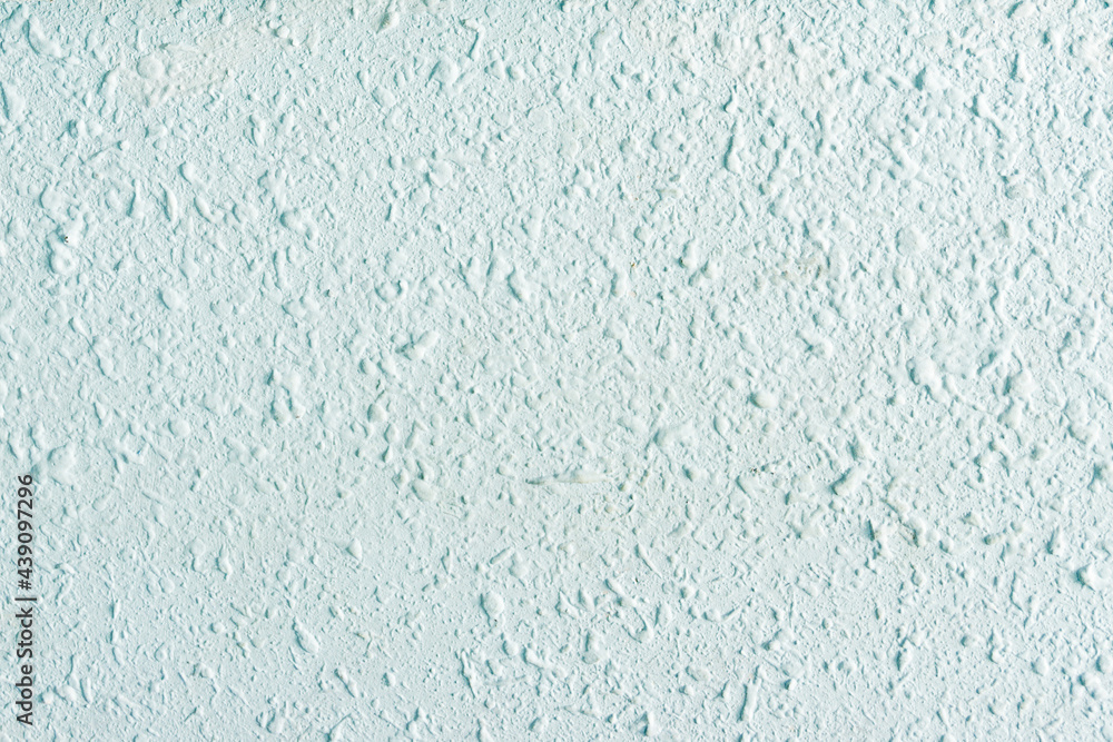 Rough rough plastered wall painted in pastel turquoise.