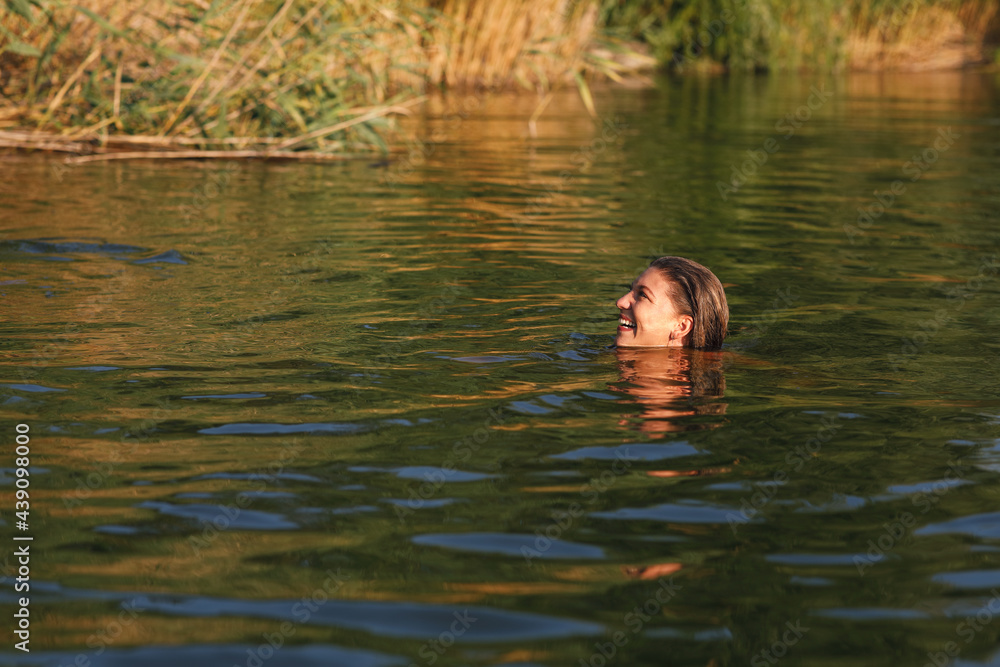 Young woman enjoys a summer day swimming in the river