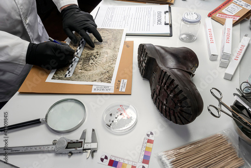 Foto Police scientist investigates a shoe sole tape tread involved in crime lab murde
