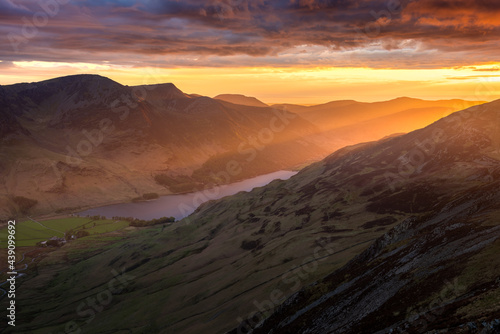 Spectacular Lake District sunset with beautiful glowing rays of light shining onto mountains and valley of Buttermere. Rugged British landscape with dramatic clouds in sky.