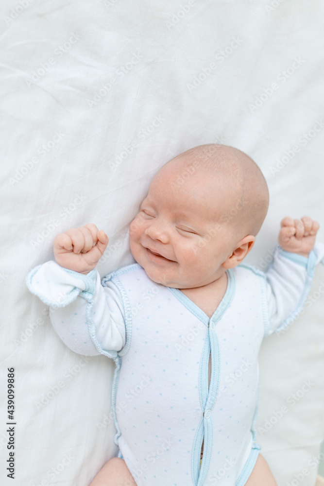 smiling or laughing in a dream, a newborn baby boy sleeps for seven days in a cot at home on a cotton bed, close-up smiling or laughing in a dream, a newborn baby boy sleeps for seven days in a cot at home on a cotton bed, close-up