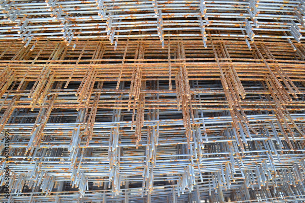 Stacks of square metal and rusty reinforcement bars and mesh for building construction. The reinforcing frame of the base plate.Civil engineering. Construction site.Metal corrosion.