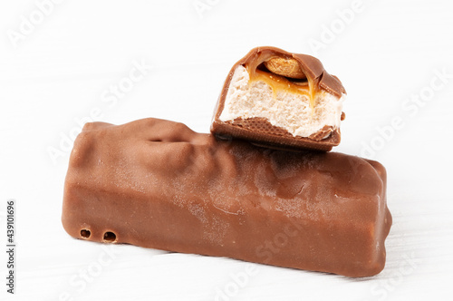 Two chocolate ice cream bars with caramel and peanuts on white background close up macro shot