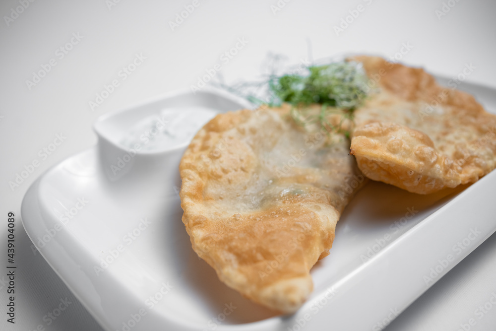 cheburek or fried dough pie with meat feeling and sauce on white background