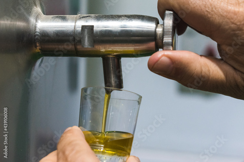 Closeup of a man's hand opening an extra virgin olive oil tap photo