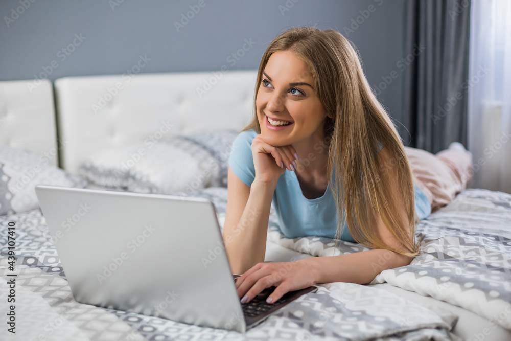 Beautiful woman enjoys using laptop at her bedroom . Beautiful woman enjoys using laptop at her bedroom .
