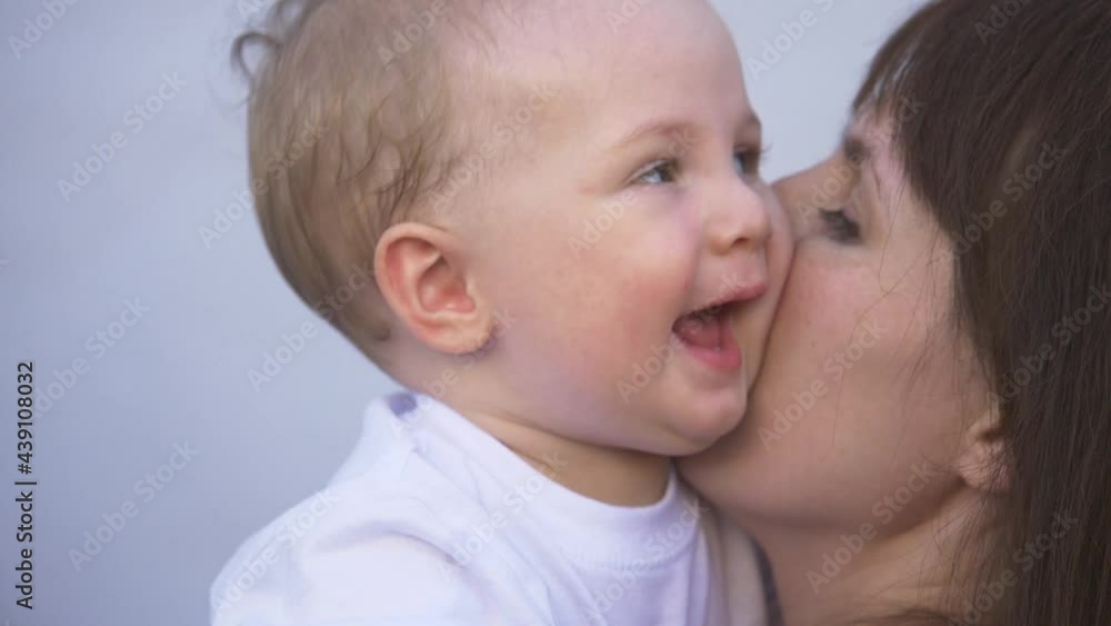 loving caring mother holds a happy baby, hugs, kisses a small child. Happy affectionate mother hugs her boy son, takes care of the child at home. Mother kissing her baby loving caring mother holds a happy baby, hugs, kisses a small child. Happy affectionate mother hugs her boy son, takes care of the child at home. Mother kissing her baby