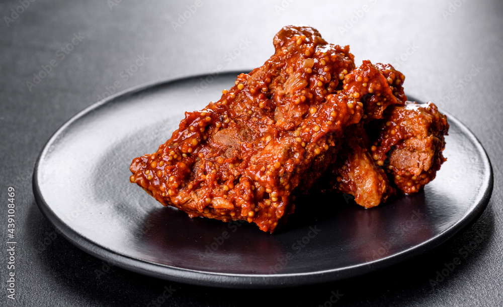 Delicious fresh baked pork ribs with orange on a black plate Delicious fresh baked pork ribs with orange on a black plate