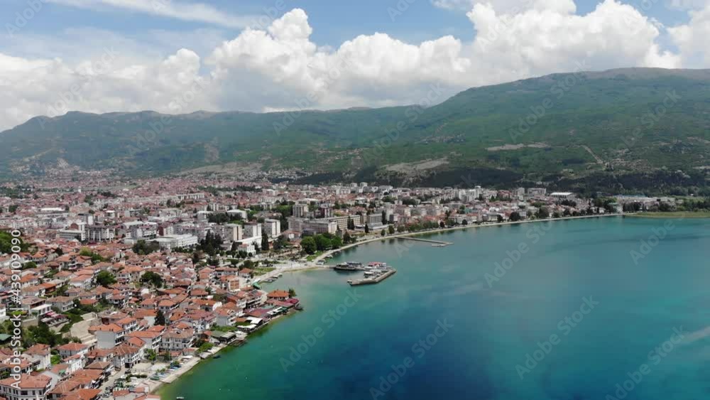Drone view of the resort town of Ohrid. Drone shot overlooking Lake Ohrid and a small town against the backdrop of green mountains. A pier with boats in the center of Ohrid, a view from above. Drone view of the resort town of Ohrid. Drone shot overlooking Lake Ohrid and a small town against the backdrop of green mountains. A pier with boats in the center of Ohrid, a view from above.