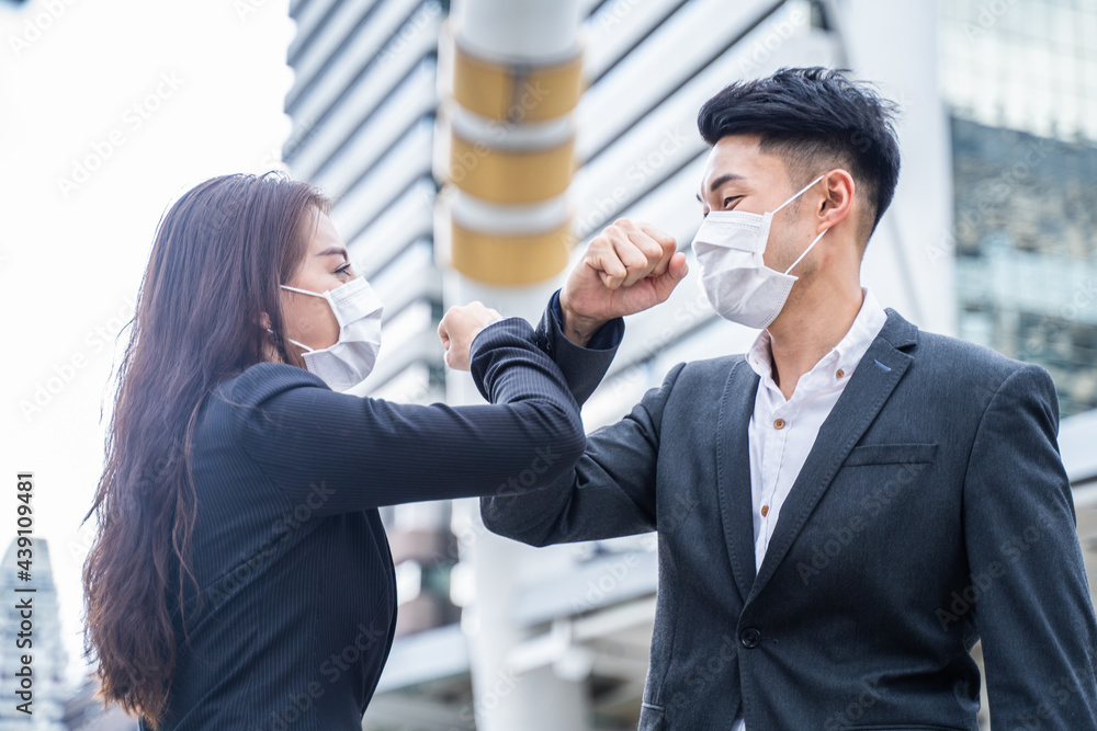 Asian businesspeople wear mask and elbow bump to avoid Covid infection Asian businesspeople wear mask and elbow bump to avoid Covid infection