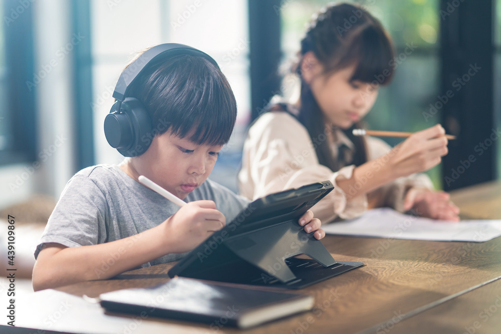 Asian homeschool boy and girl learning online at home by using tablet. Asian homeschool boy and girl learning online at home by using tablet.