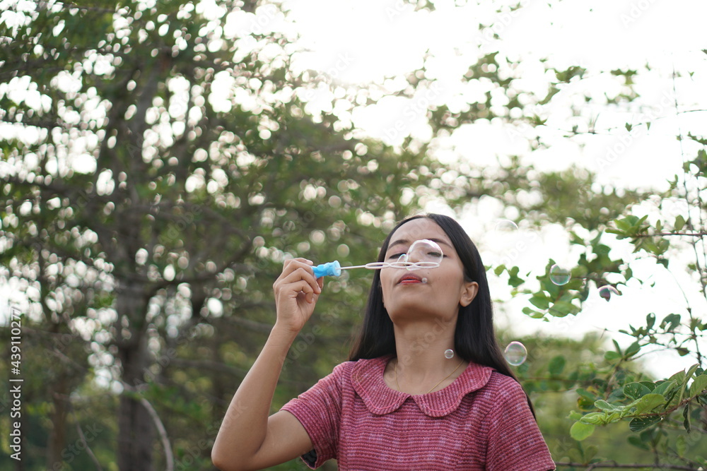 Asian woman blowing soap bubbles every green grass background