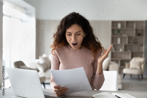 Vászonkép Happy excited Latino woman shocked by good news in paper correspondence working online on laptop at home office
