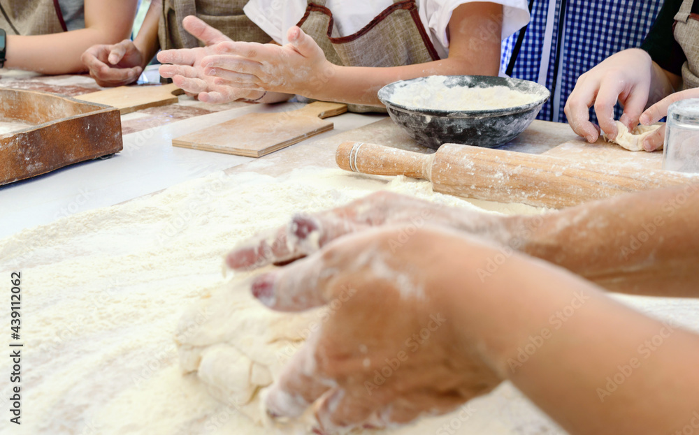 The cook teaches children to making dough. The female hand kneads the dough on a floured table. Master class in baking. Cooking at home. The cook teaches children to making dough. The female hand kneads the dough on a floured table. Master class in baking. Cooking at home.