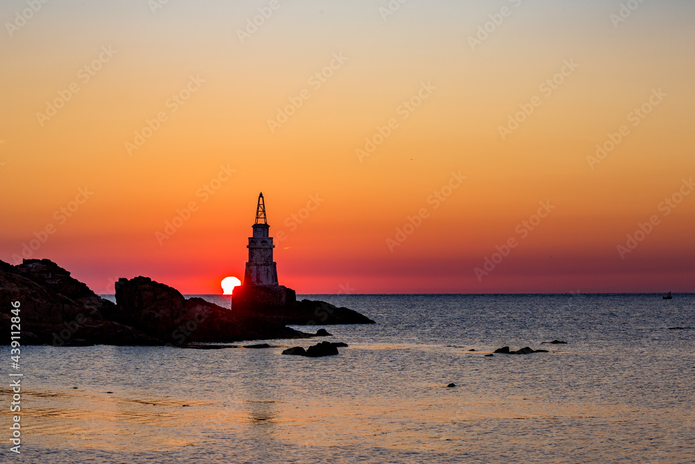 Sun rising behind the lighthouse of Ahtopol, Bulgaria.
Black Sea. Silhouette and cloudless colorful sky.