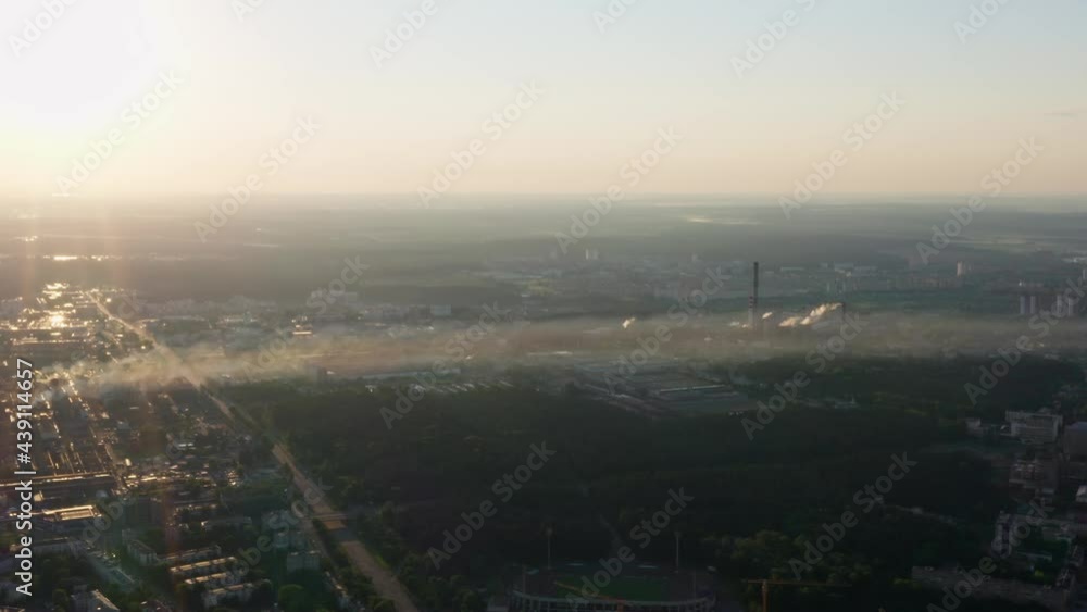 Aerial view sunrise or sunset in city, morning or evening cityscape. Drone flight over industrial district. Bright sun in sky on horizon. City skyline. Thermal power station and factories from above Aerial view sunrise or sunset in city, morning or evening cityscape. Drone flight over industrial district. Bright sun in sky on horizon. City skyline. Thermal power station and factories from above