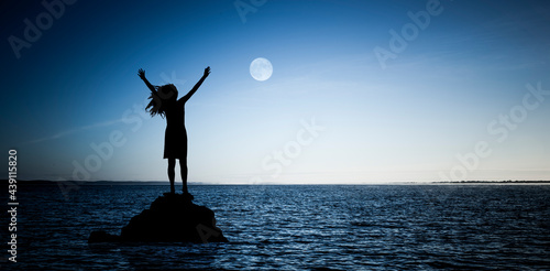 Frau auf einem Felsen im Wasser bei Vollmond