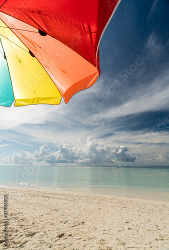 Colorful umbrella on paradise white sand beach and blue sky in sandbank island, Maldives.