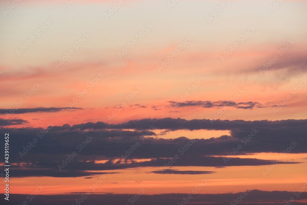 Beautiful pink orange sunset in the sky with black clouds on horizon, natural sky background