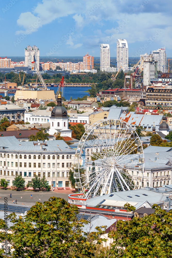 The landscape of summer Kyiv with a view of the old district of Podil with a Ferris wheel.
