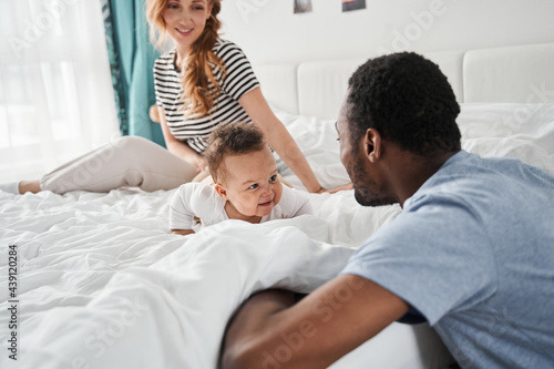 Family having fun with their kid on the bed while playing
