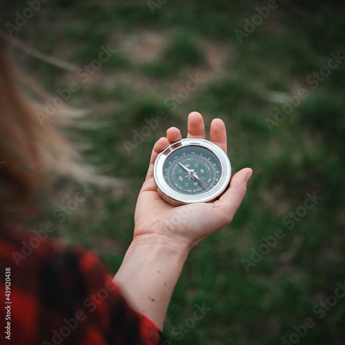 A girl in a red checkered shirt holds a compass in hand and is guided by the area, walk,hiking