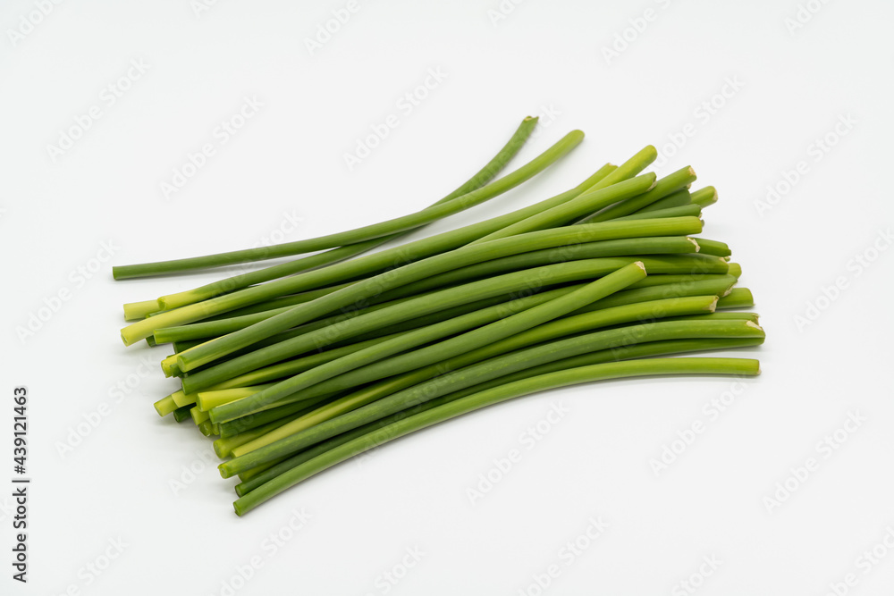 Green garlic stalks on white background.
