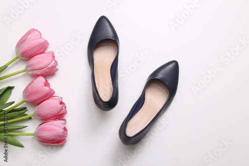 Women's shoes with heels and a bouquet of pink tulips on white background