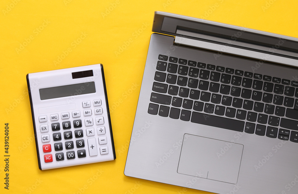 Calculator and laptop on a yellow background. Top view Calculator and laptop on a yellow background. Top view