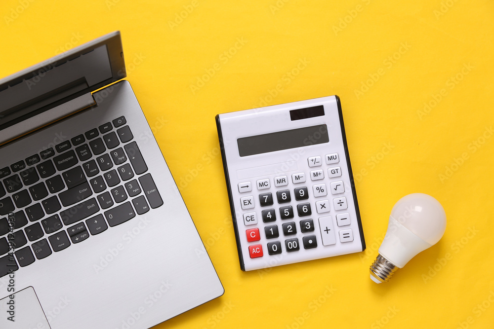 Laptop, Calculator and led light bulb on yellow background. Top view. Flat lay. Laptop, Calculator and led light bulb on yellow background. Top view. Flat lay.